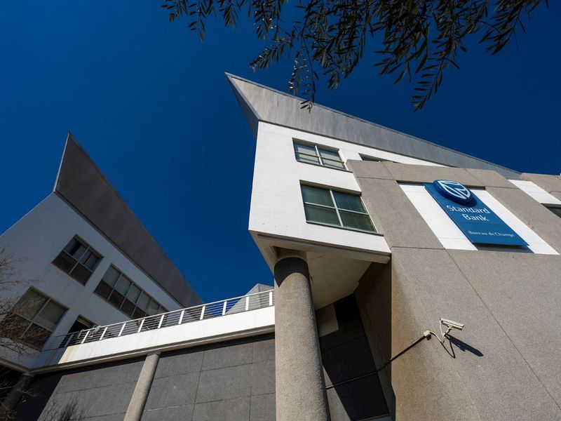 Low-angle exterior view of a modern commercial building facade featuring concrete cladding, large windows, and prominent corporate signage.