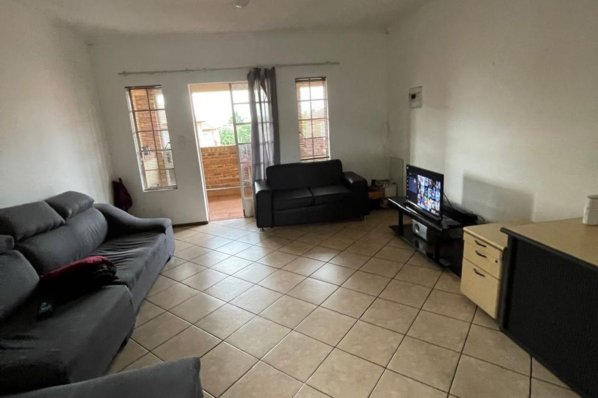 Spacious living room featuring neutral tiled flooring and a sliding glass door providing access to an outdoor balcony area.