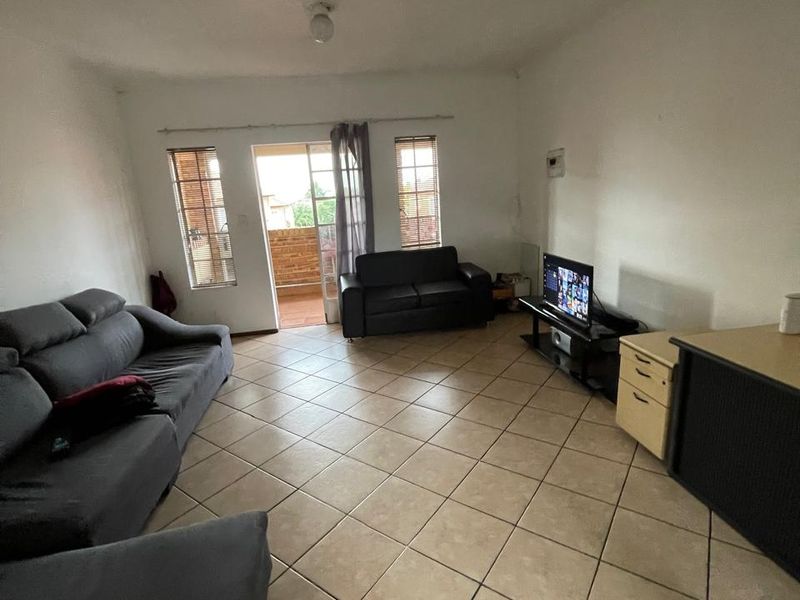 Spacious living room featuring neutral tiled flooring and a sliding glass door providing access to an outdoor balcony area.