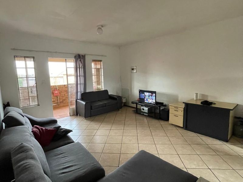 Spacious living room featuring ceramic floor tiles and direct access to an outdoor balcony through a sliding glass door.