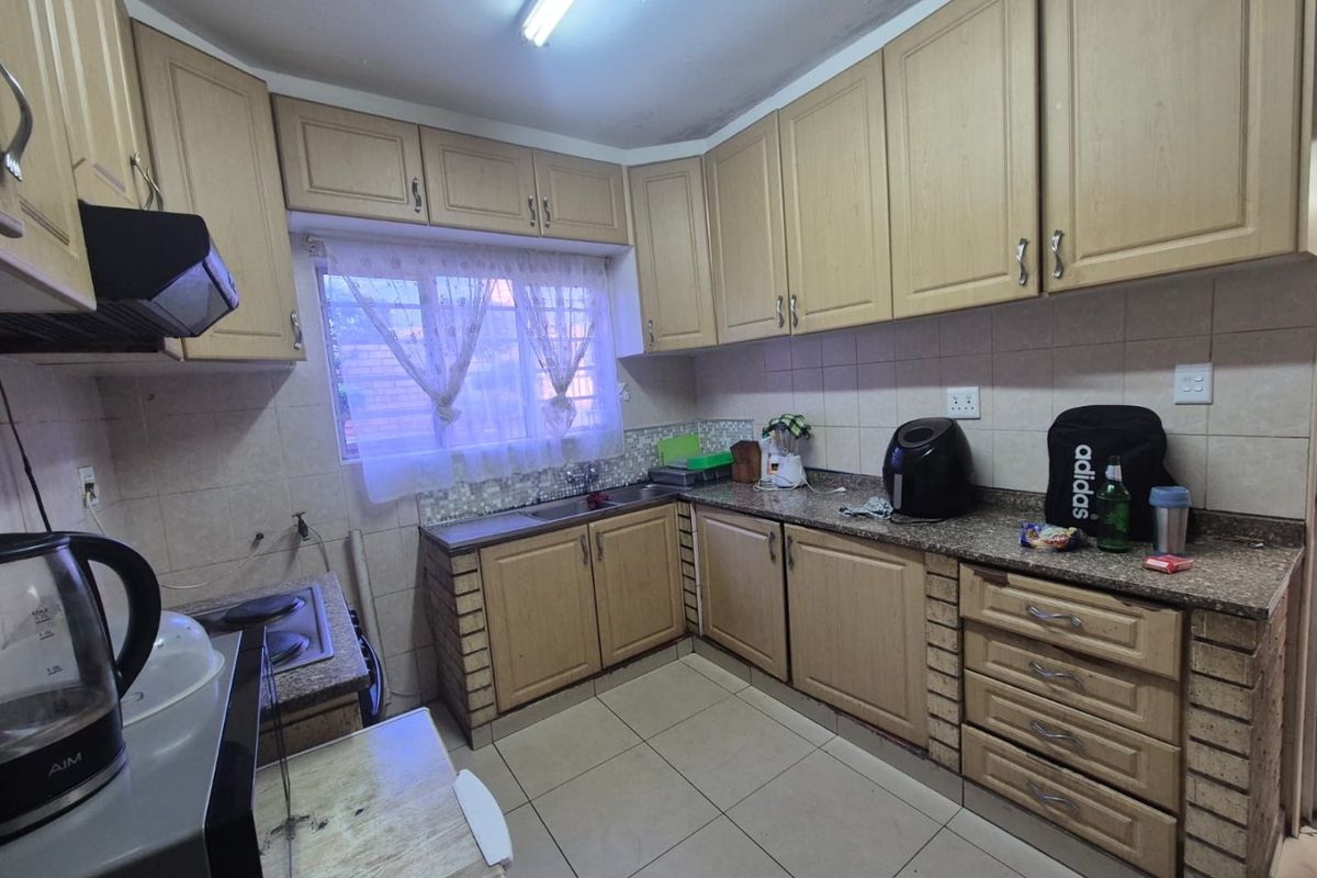 A functional kitchen featuring laminate cabinetry, granite countertops, tiled backsplash, and ceramic flooring, offering a practical layout with built-in appliances.