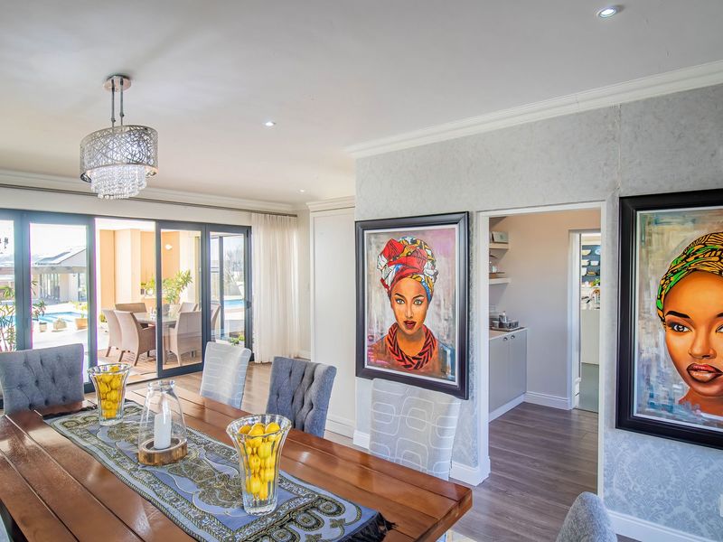 Spacious dining room featuring elegant wallpaper, recessed lighting, and large sliding glass doors that provide seamless access to the outdoor patio and pool area.