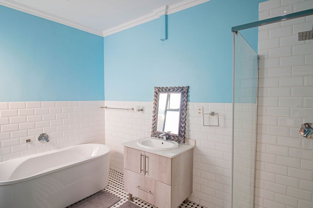 Modern bathroom featuring a freestanding bathtub, a separate walk-in shower with subway tiling, and a vanity unit with a basin.