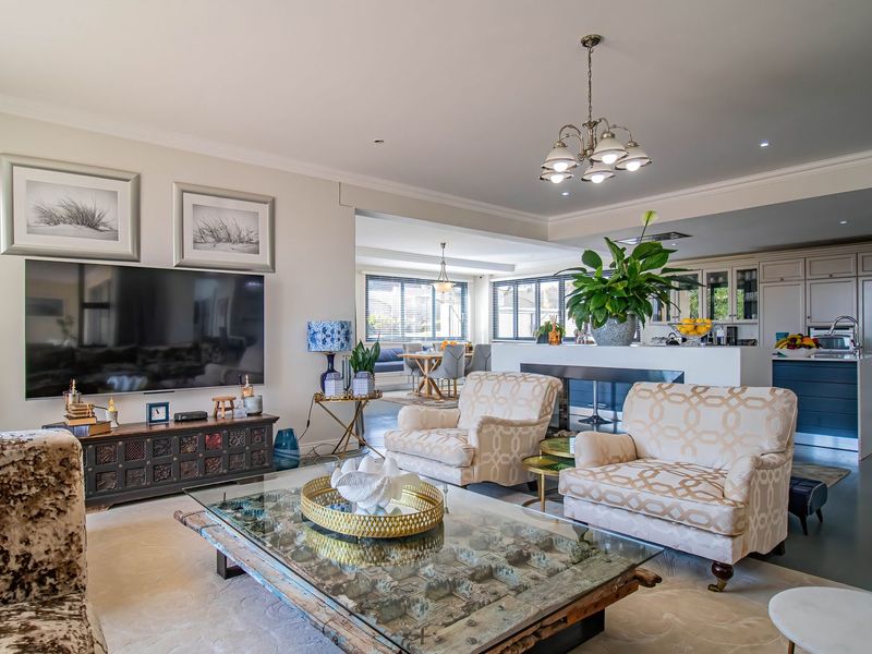 Spacious open-plan living area featuring a modern kitchen with island, integrated cabinetry, and elegant lighting, seamlessly flowing into a comfortable lounge space.