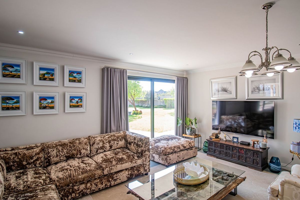 A well-maintained living room featuring recessed lighting, coving, and a large sliding glass door providing direct access to the rear garden.