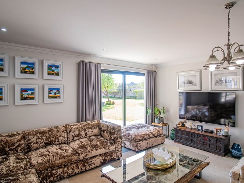 A well-maintained living room featuring recessed lighting, coving, and a large sliding glass door providing direct access to the rear garden.