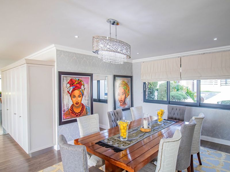 A well-appointed dining room featuring crown molding, recessed lighting, a decorative chandelier, and built-in cabinetry, with a view into the adjacent living area.