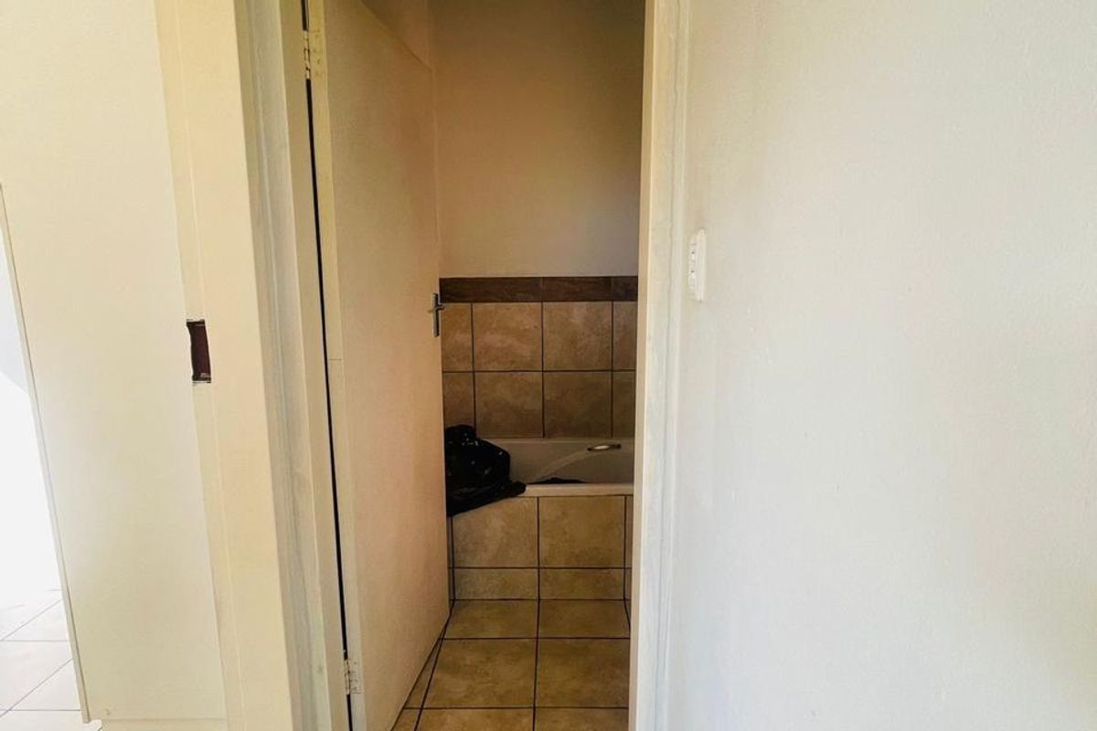 A view into a bathroom featuring tiled flooring and a built-in bathtub with tiled surround.
