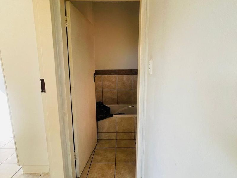 A view into a bathroom featuring tiled flooring and a built-in bathtub with tiled surround.