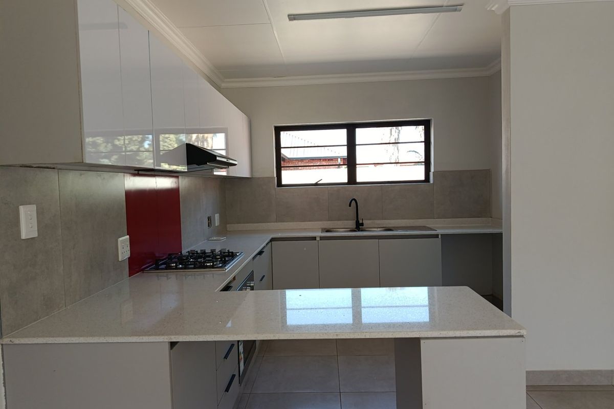Modern kitchen featuring sleek white cabinetry, quartz countertops, a gas hob with extractor fan, and a double sink with a contemporary mixer tap.