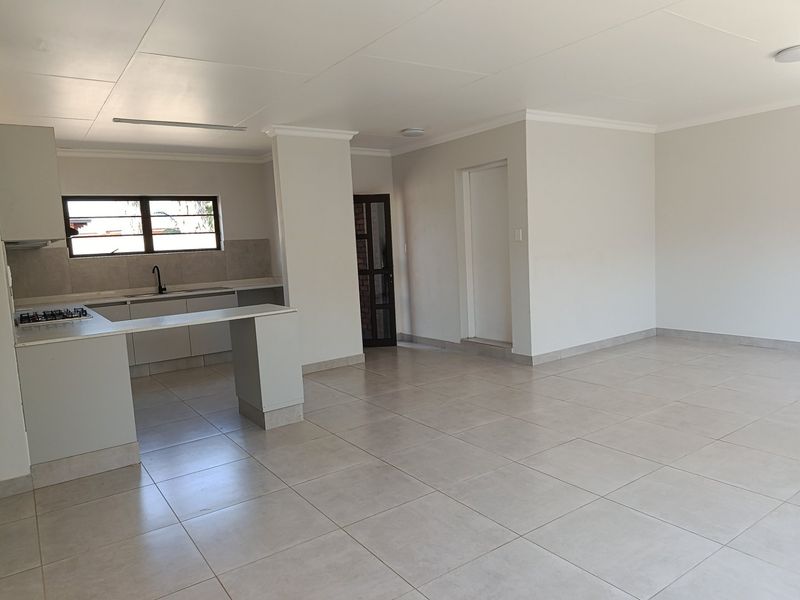 Spacious open-plan living area featuring a modern kitchen with built-in cabinetry, gas hob, extractor fan, and tiled flooring throughout.