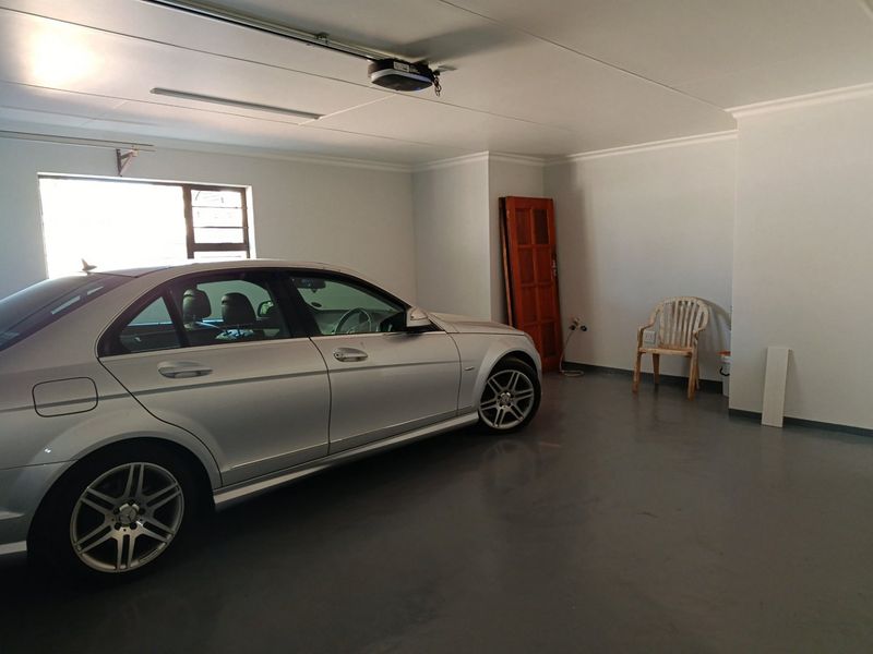 A clean, spacious garage featuring an epoxy-coated floor, coved ceiling, and an automated door motor.