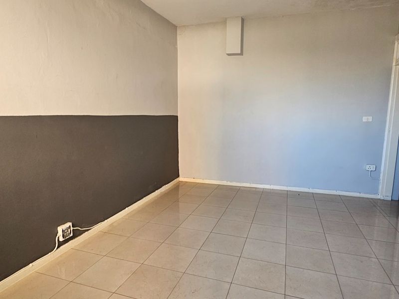 An empty living area featuring neutral ceramic floor tiles and two-tone painted walls, providing a blank canvas for interior design.