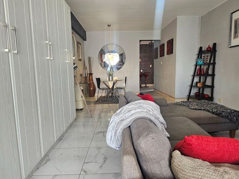 Open plan living and dining area featuring modern tiled flooring and extensive built-in cabinetry for storage.