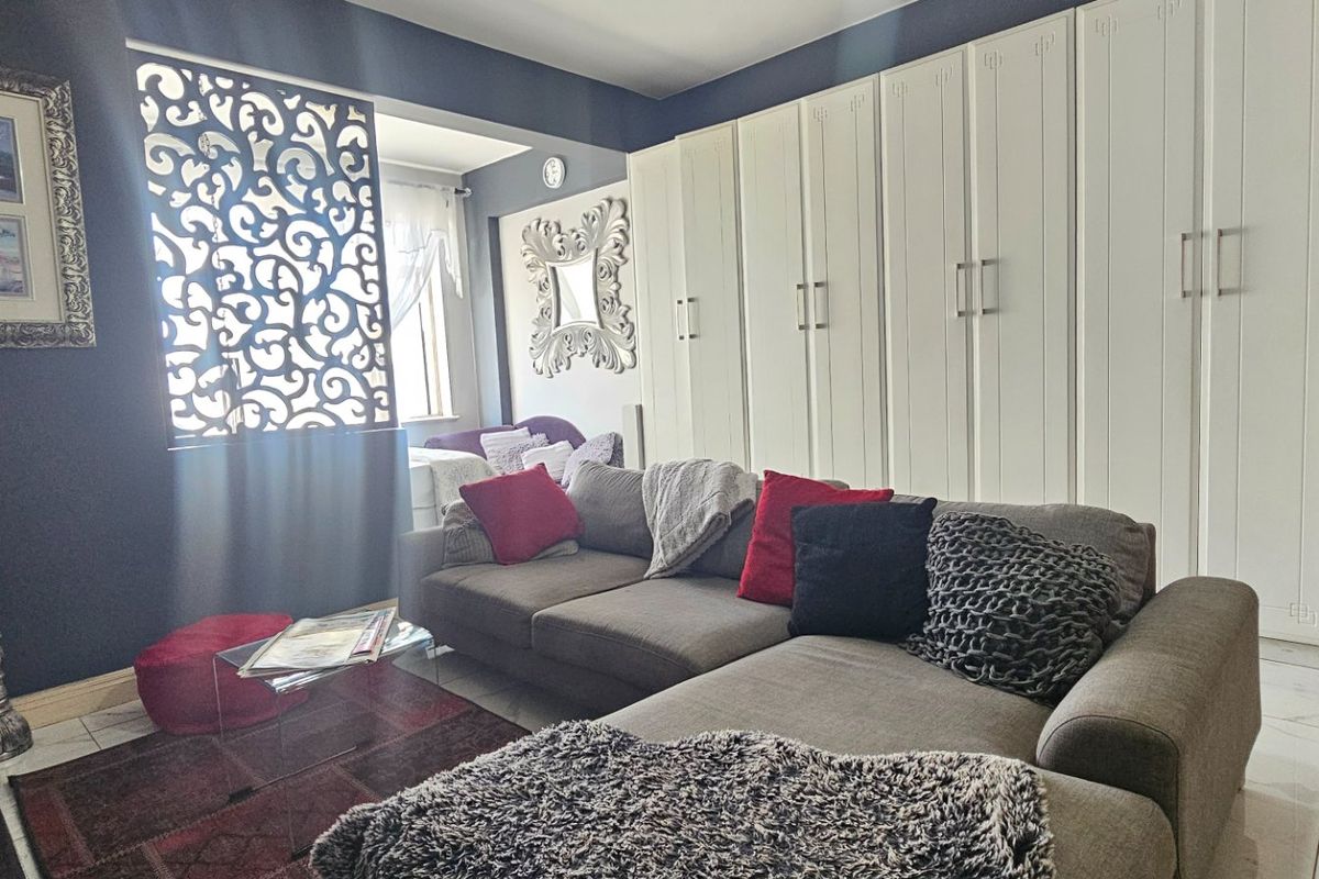 A well-maintained living room featuring extensive built-in floor-to-ceiling cabinetry, decorative screen detailing, and polished tiled flooring.