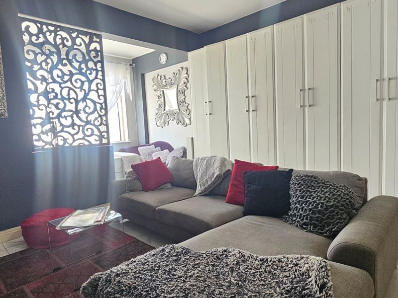 A well-maintained living room featuring extensive built-in floor-to-ceiling cabinetry, decorative screen detailing, and polished tiled flooring.