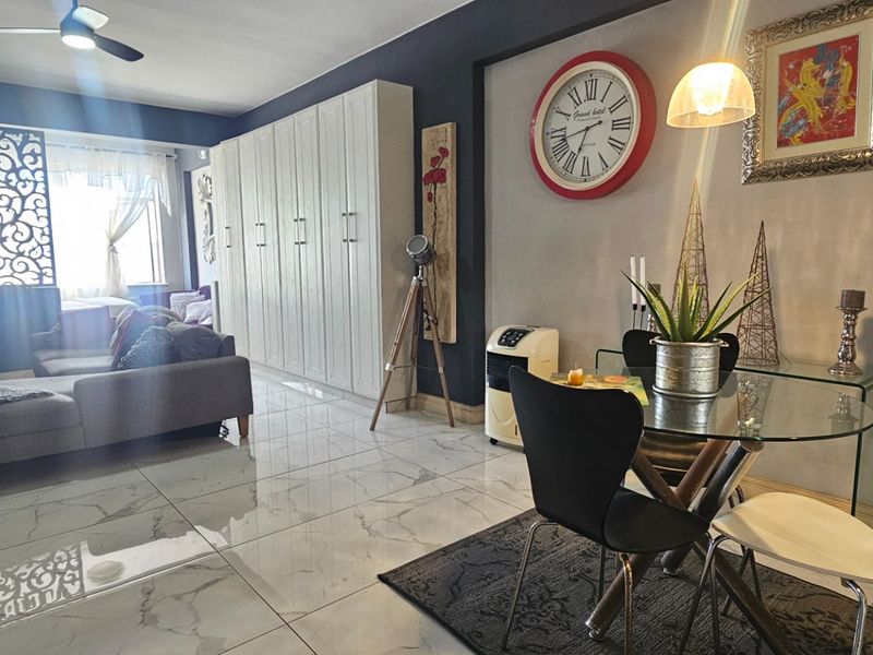 Open-plan living and dining area featuring large-format tiled flooring, built-in storage cabinetry, and a ceiling fan.