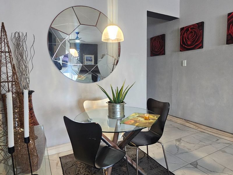 A dining area featuring marble-look floor tiles, neutral wall finishes, and a modern pendant light fixture.