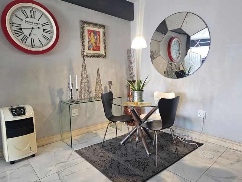A dining area featuring polished marble-look floor tiles, neutral wall finishes, and a modern pendant light fixture.