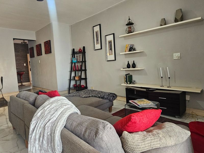 Open-plan living and dining area featuring polished marble-look floor tiles and modern floating wall shelving.