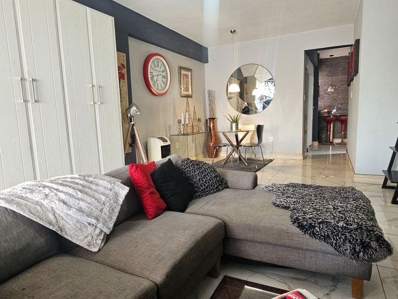 Open plan living and dining area featuring tiled flooring and built-in cabinetry, leading through to a secondary kitchen space.