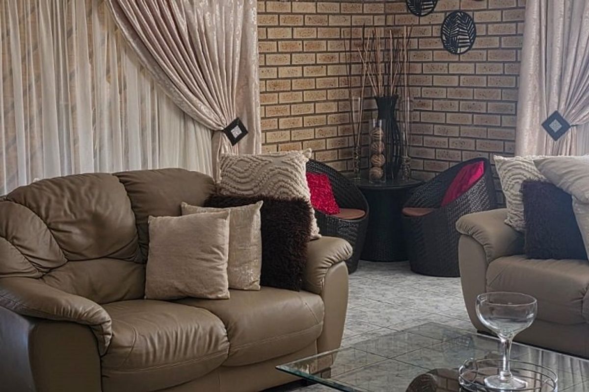 A comfortable living room featuring a textured exposed brick feature wall and neutral tiled flooring, offering a warm and inviting atmosphere.