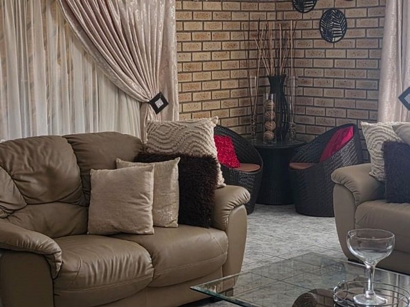 A comfortable living room featuring a textured exposed brick feature wall and neutral tiled flooring, offering a warm and inviting atmosphere.