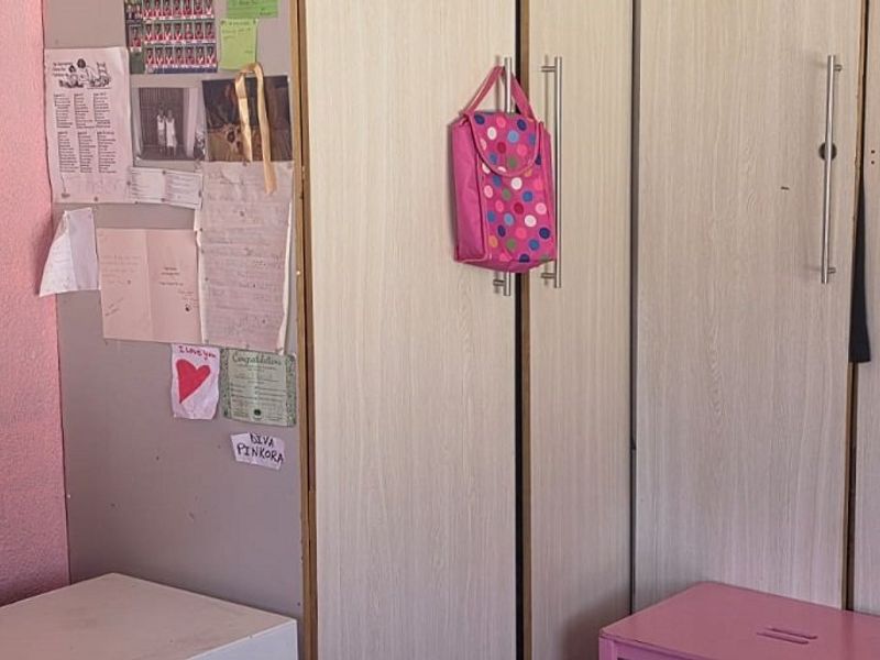 A bedroom featuring built-in cupboards with light wood-grain finish and modern metal handles.