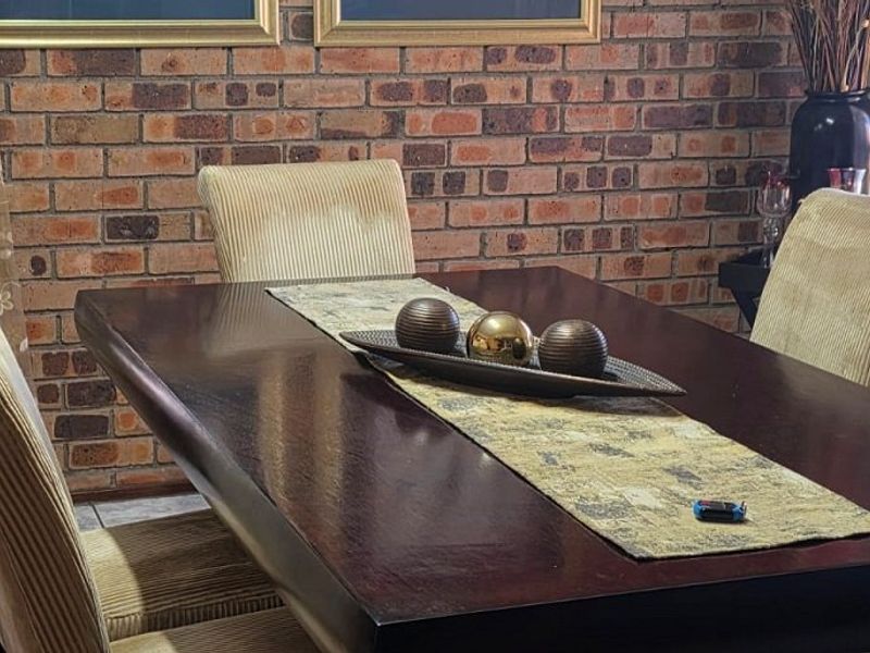 A dining room area featuring a prominent exposed brick feature wall and tiled flooring, providing a rustic aesthetic.