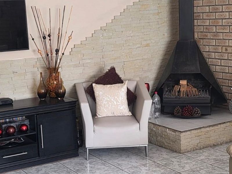 Living room featuring a stone-clad feature wall, a built-in corner fireplace, and tiled flooring.