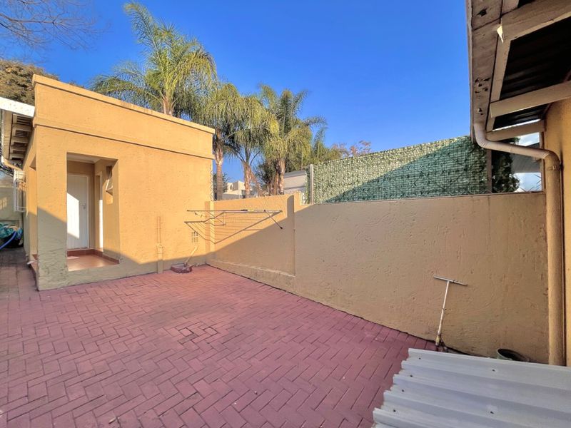 A private rear courtyard featuring paved flooring, boundary walls, and a wall-mounted clothesline, offering a functional outdoor space.