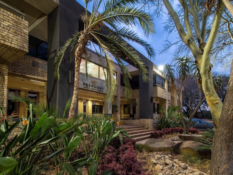 Front facade of a commercial building featuring brick masonry, modern dark architectural accents, and well-maintained landscaped gardens at the entrance.