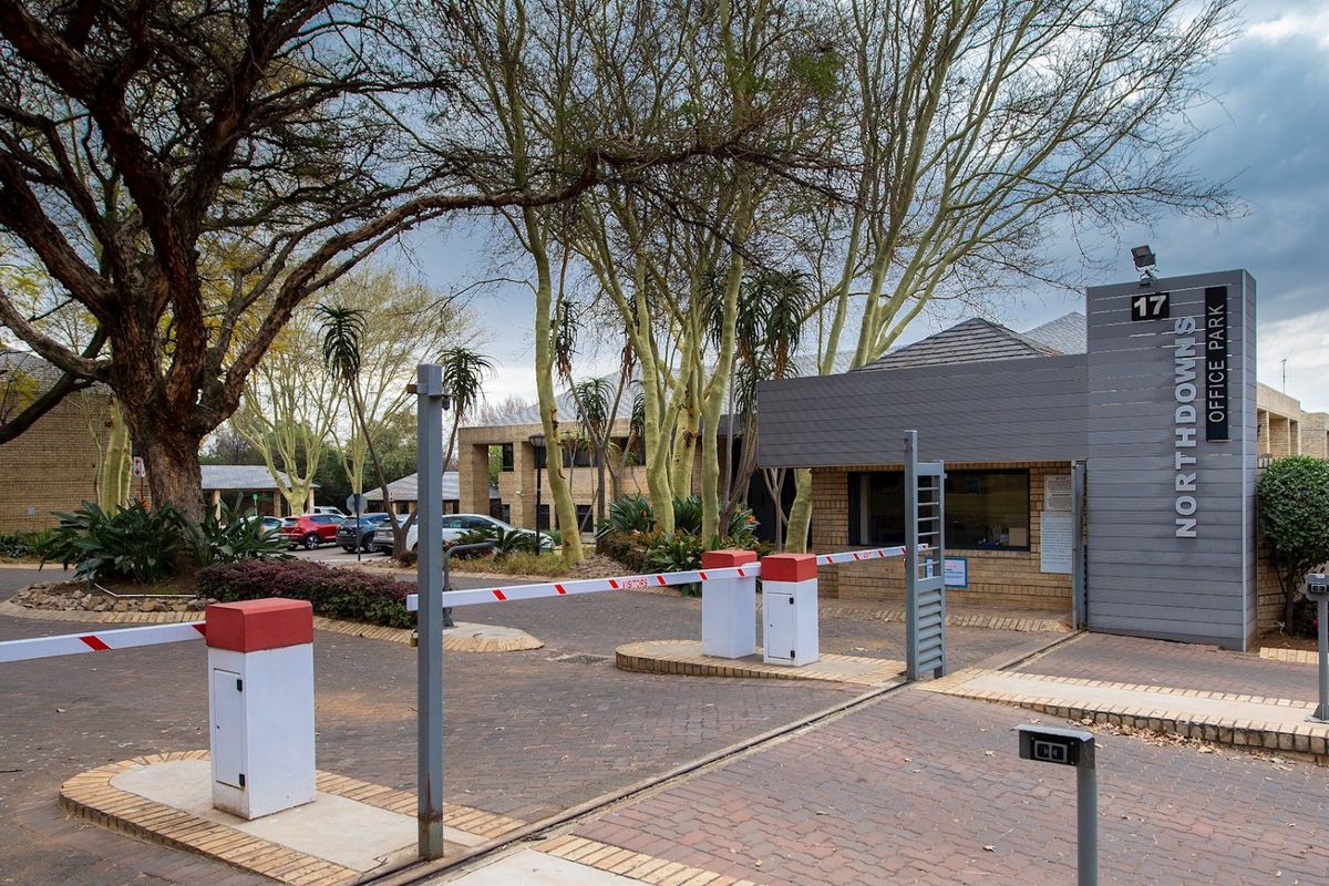 The entrance to Northdowns Office Park featuring a secure boom gate, guard house, and paved driveway access.
