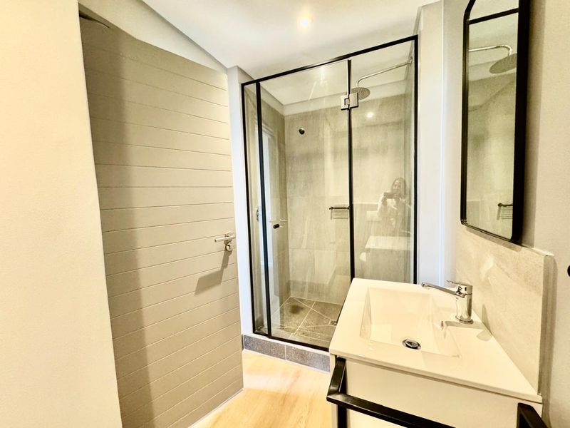 Modern bathroom featuring a glass-enclosed shower with a rain shower head, a sleek vanity basin, and contemporary finishes throughout.