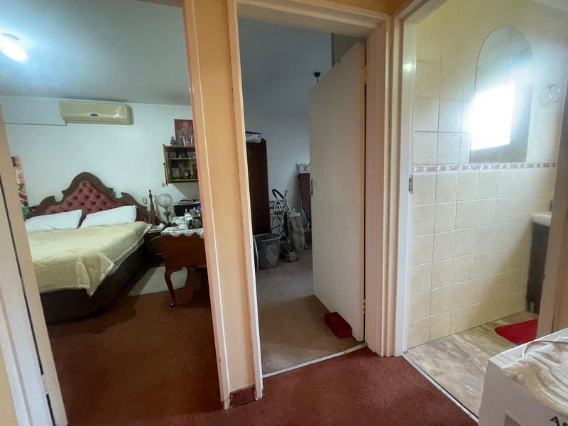 A hallway view showing access to a bedroom and bathroom, featuring carpeted flooring and dated interior finishes.