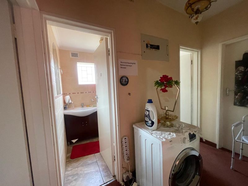 A hallway area featuring tiled flooring, an electrical distribution board, and access to an adjacent bathroom.