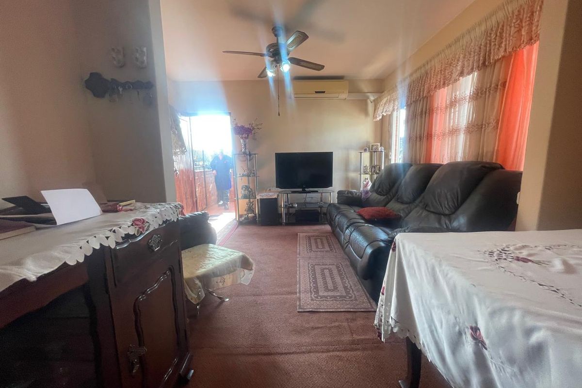A living room featuring carpet flooring, a ceiling fan, and a wall-mounted split-system air conditioner, with direct access to an outdoor area.