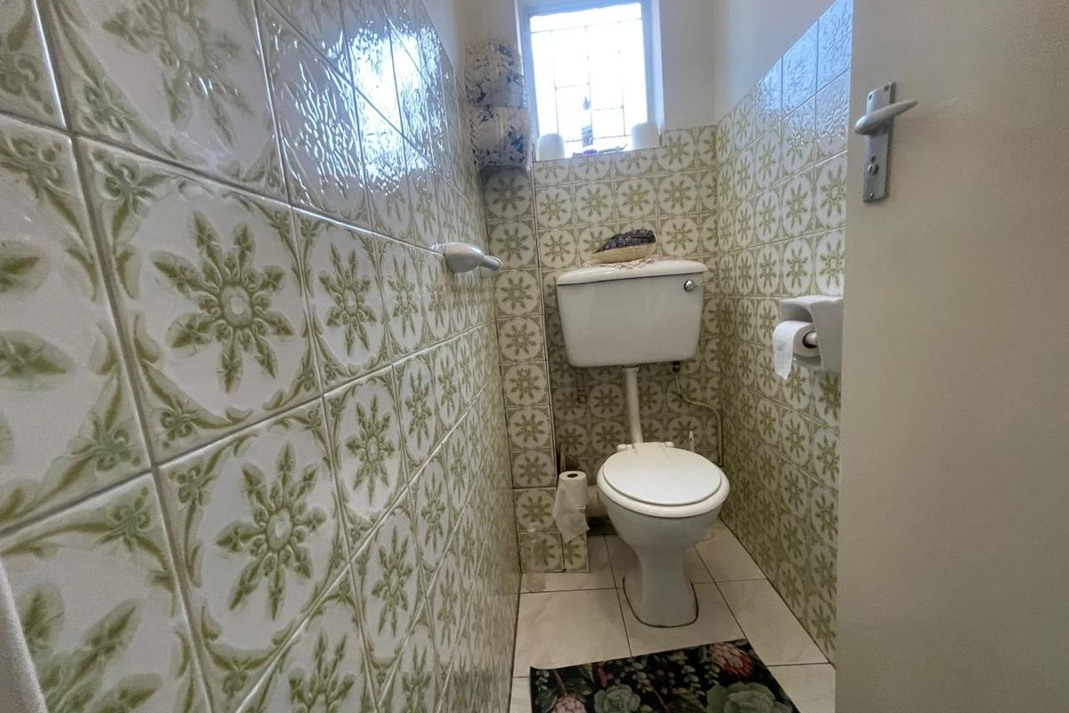 A compact guest bathroom featuring vintage patterned ceramic wall tiles and standard white sanitaryware.