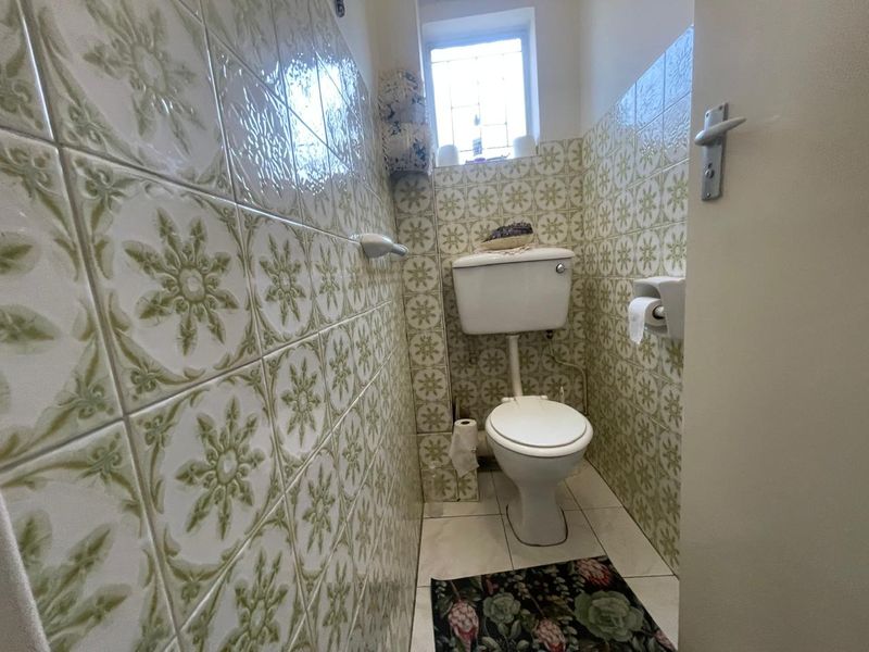 A compact guest bathroom featuring vintage patterned ceramic wall tiles and standard white sanitaryware.
