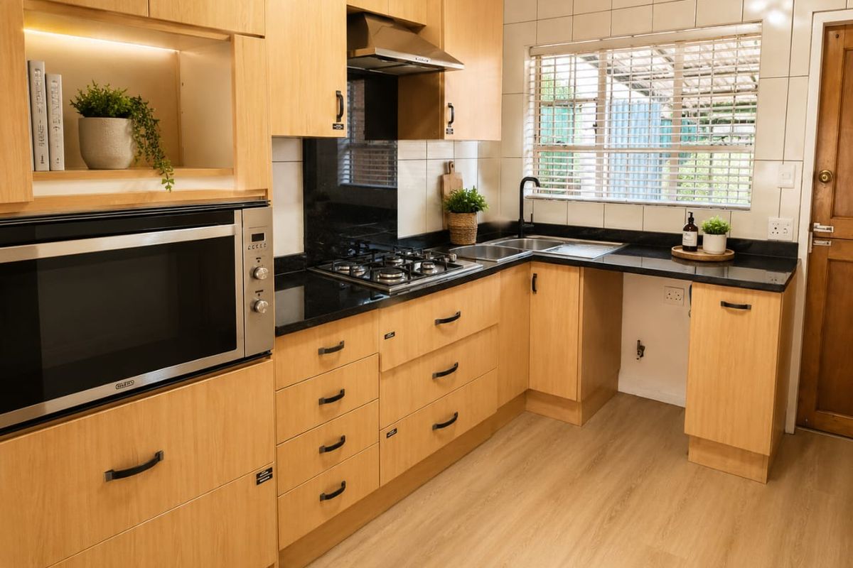 Modern kitchen featuring light wood cabinetry, granite countertops, a gas hob, built-in oven, and a tiled backsplash with a functional layout.