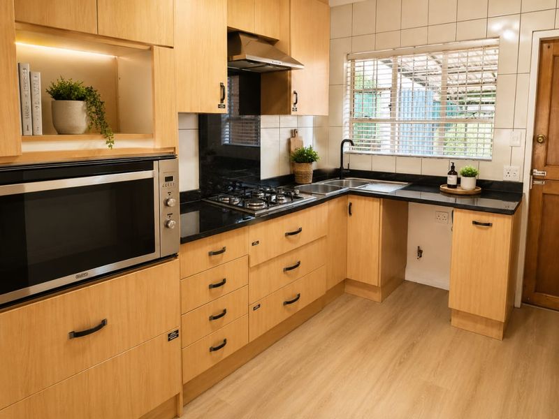 Modern kitchen featuring light wood cabinetry, granite countertops, a gas hob, built-in oven, and a tiled backsplash with a functional layout.