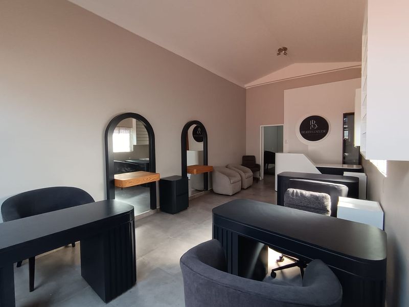 A well-maintained commercial salon space featuring tiled flooring, built-in arched vanity mirrors, and a dedicated reception area.
