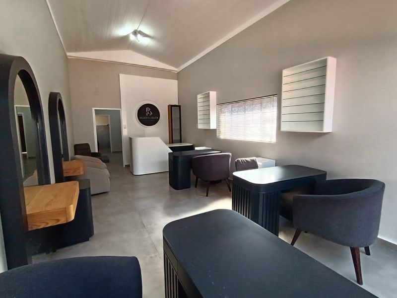 A well-maintained commercial salon space featuring tiled flooring, built-in reception desk, wall-mounted display shelving, and professional lighting.