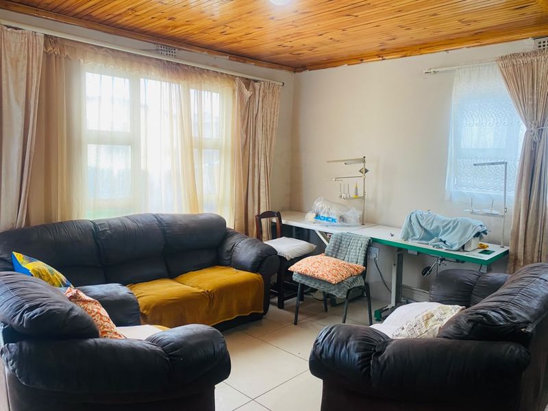 A living room featuring tiled flooring and a timber tongue and groove ceiling, offering a functional space with potential for modernization.