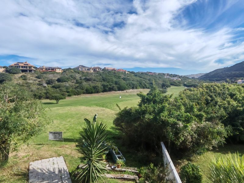 A scenic elevated view overlooking a lush green golf course and surrounding hillside residential landscape.