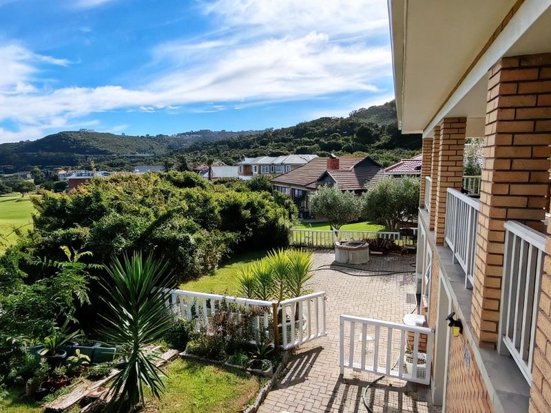 A spacious paved patio area featuring brick pillars and a white balustrade, offering scenic views of the surrounding landscape and golf course.