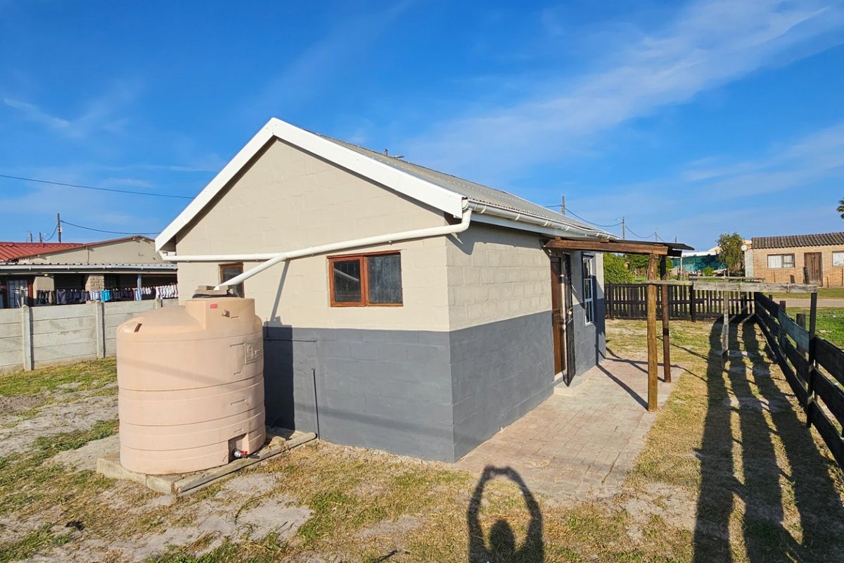 Rear view of the property featuring a paved patio area, timber pergola, and an external water storage tank connected to the gutter system.