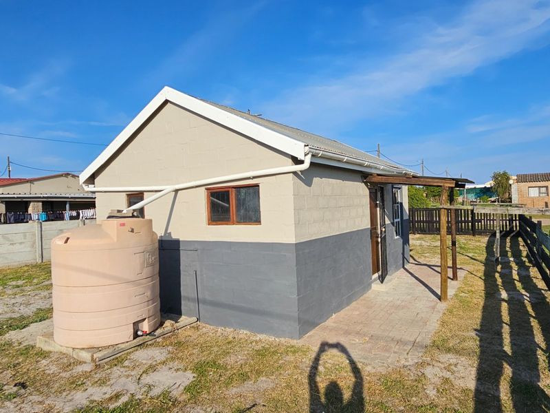 Rear view of the property featuring a paved patio area, timber pergola, and an external water storage tank connected to the gutter system.