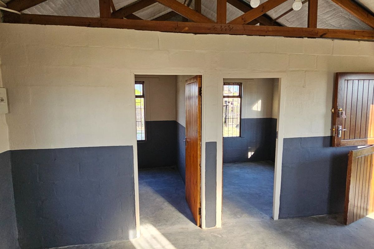 A utility space featuring exposed timber roof trusses, concrete flooring, and dual access points with stable-style timber doors.