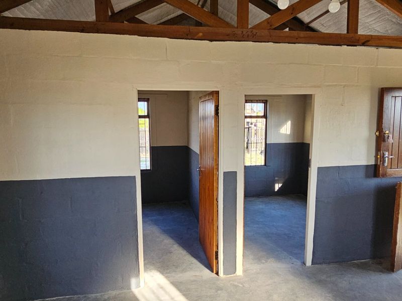 A utility space featuring exposed timber roof trusses, concrete flooring, and dual access points with stable-style timber doors.
